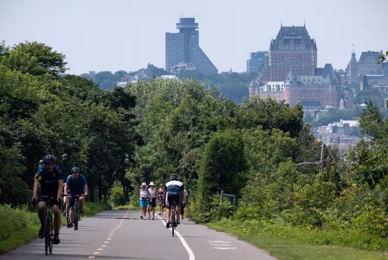 Cyclistes sur la Route verte 1, parcours des Anses, à Lévis, avec vue sur la ville de Québec et le Château Frontenac