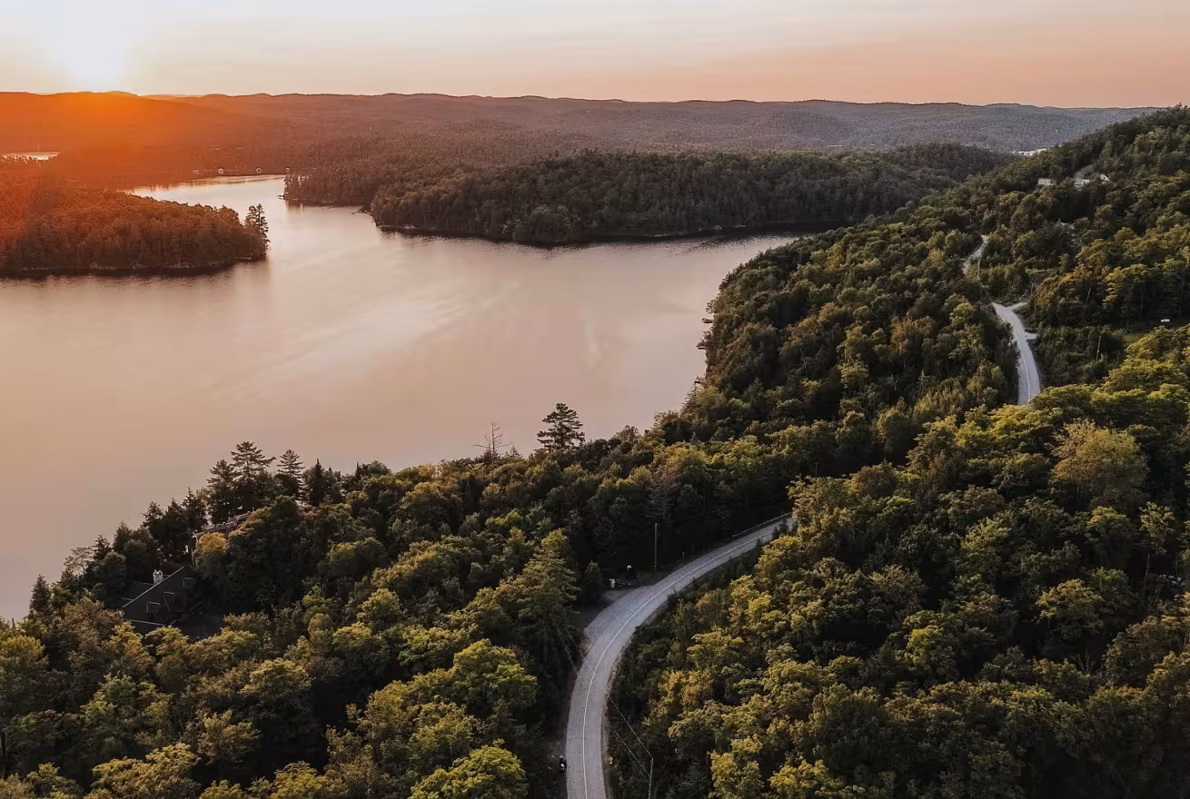 Vue sur un lac et une route de l'Outaouais au coucher de soleil