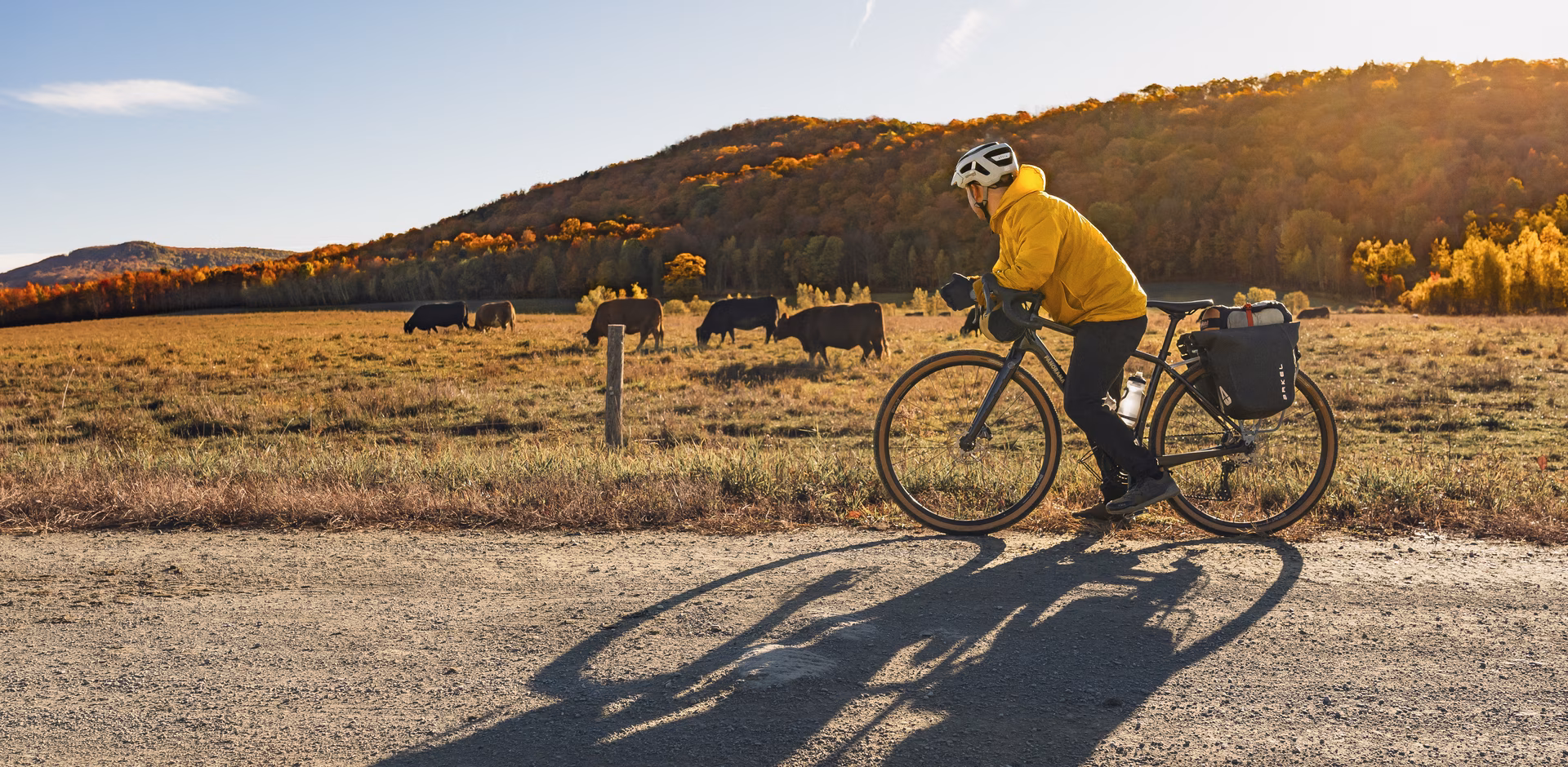 Un cycliste prend une pause au soleil sur une route non asphalté à l'automne