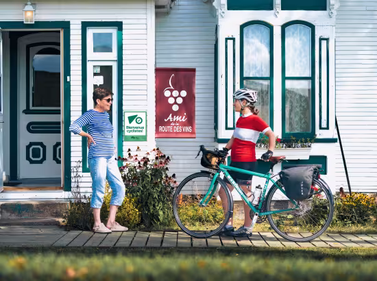 Une aubergiste attestée Bienvenue cyclistes! accueille une cycliste en cyclotourisme pour passer la nuit dans son établissement.