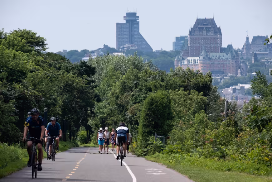 Cyclistes sur la Route verte 1, parcours des Anses, à Lévis, avec vue sur la ville de Québec et le Château Frontenac