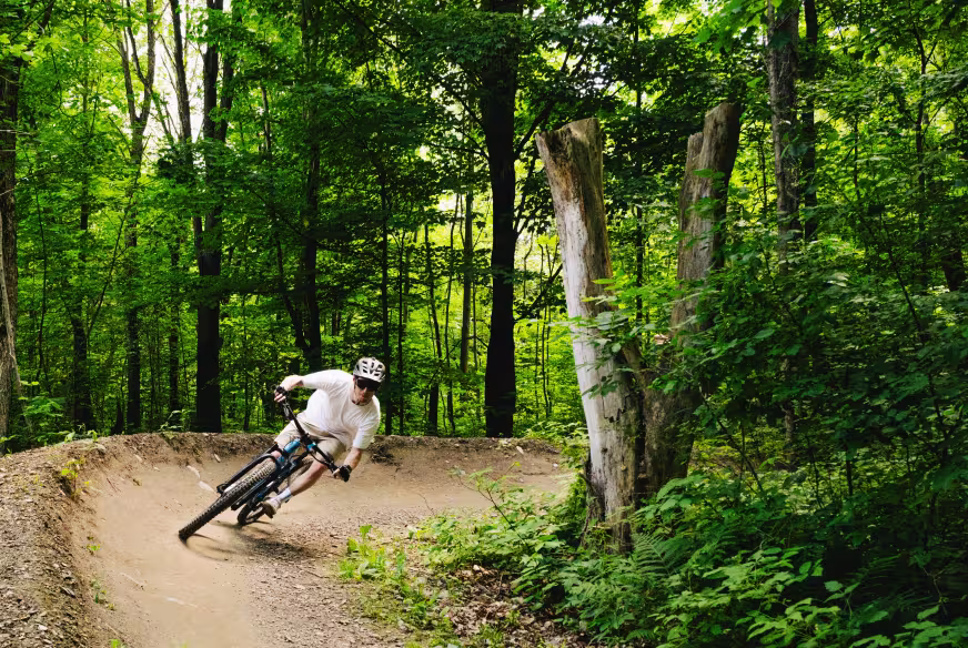 Un cycliste de vélo de montagne suit une courbe sur un sentier du Parc des Sommets dans les Cantons-de-l'Est