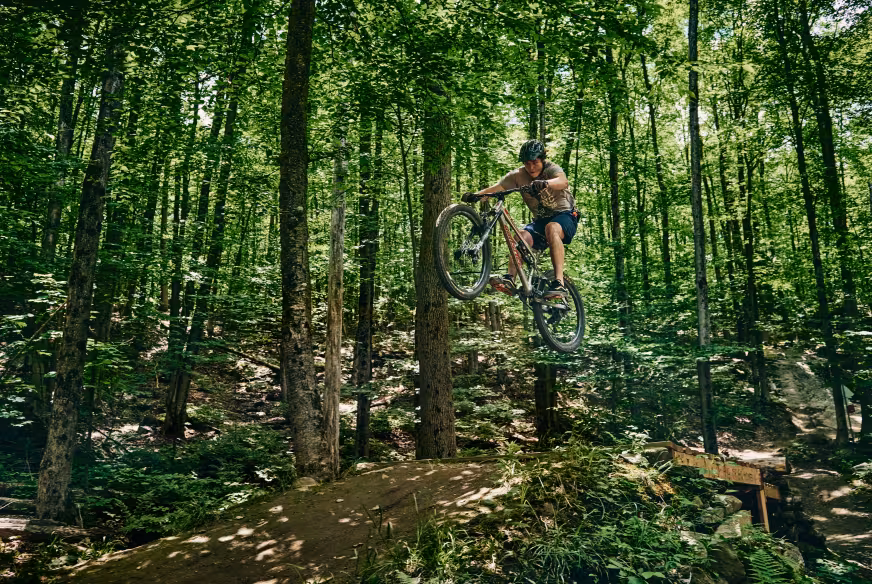 Un pratiquant de vélo de montagne réalise un saut sur un sentier dans les Cantons-de-l'Est