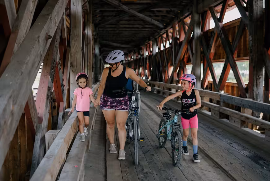 Une famille de cyclistes marchent avec leur vélo sur le Pont Félix-Gabriel-Marchand en Outaouais