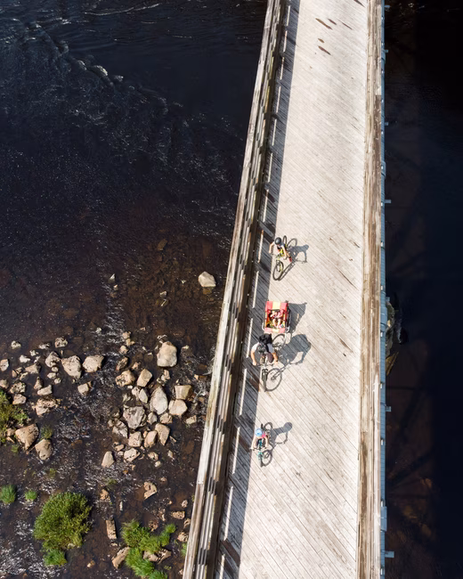 Une famille de trois cyclistes passent un pont au dessus d'un lac